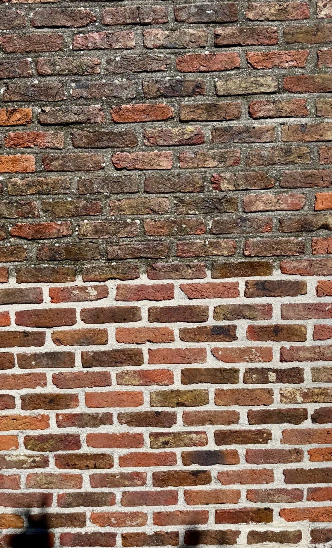Bakstenen gevel waarvan het onderste deel gereinigd is