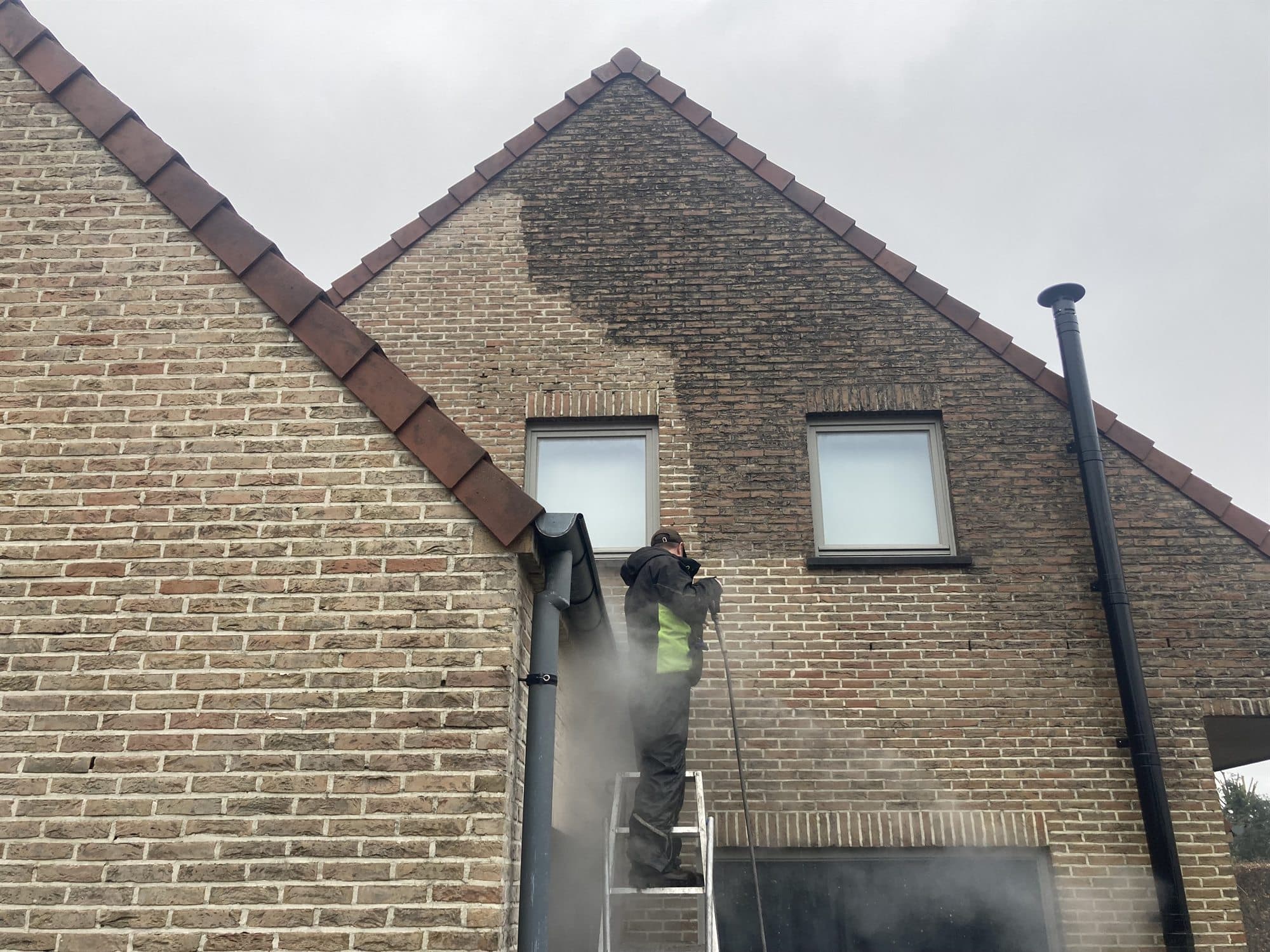 Gevelreiniging met stoom langs de zijgevel van een woning