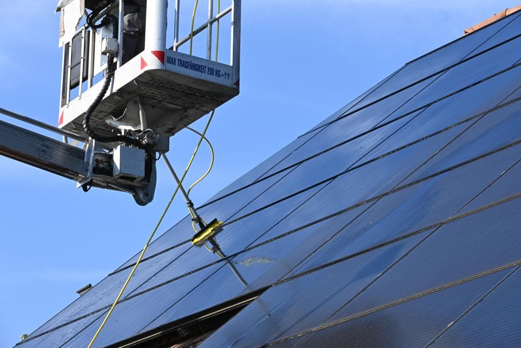 Zonnepanelen op een dak gereinigd vanop een hoogtewerker